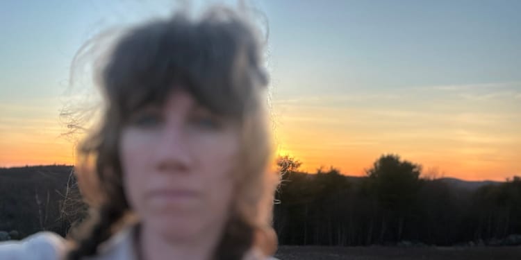 blurry faced white-skinned human with bangs in front of sunset